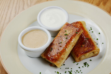 Pancakes with meat, with sauce and sour cream, decorated with herbs