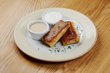 Pancakes with meat, with sauce and sour cream, decorated with herbs