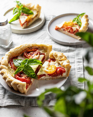 Summer puff pastry tart with tomato, mozzarella and Bazil. Vegetable quiche sliced