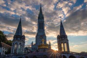 Fototapeta na wymiar The sun star among the bell towers of the pilgrimage basilica of the apparitions of Mary in Lourdes