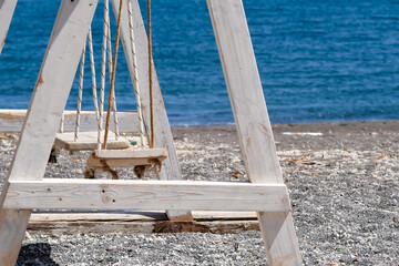 View of a wooden swing on the sandy black beach of Perissa in Santorini