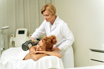 Happy young woman getting skin treatment at spa salon