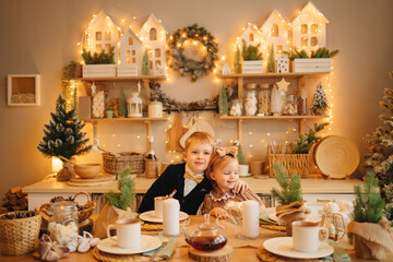 pretty little girl and boy at the kitchen table. christmas decor