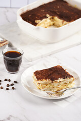 A piece of italian dessert tiramisu made of ladyfinger biscuits, mascarpone cheese, espresso on white marble background