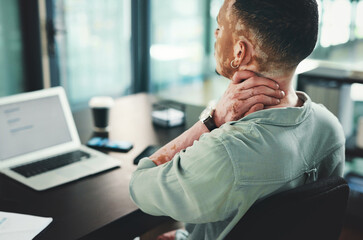Neck pain is the worst. Shot of a young businessman with neck pain while using a laptop in an...