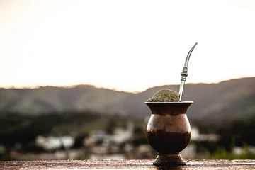 Wandcirkels tuinposter Chimarrão gourd with a small town from Rio Grande do Sul in the background, infusion of yerba mate, served on cold winter days, Symbol drink of Rio Grande do Sul, © RHJ