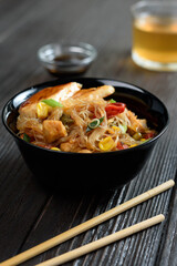 Asian rice noodles funchose with chicken, vegetables and sauce. Near chopsticks and green tea