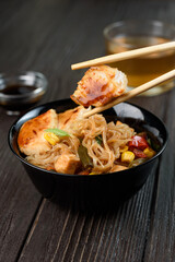 Asian rice noodles funchose with chicken, vegetables and sauce. Near chopsticks and green tea