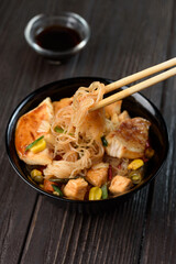 Asian rice noodles funchose with chicken, vegetables and sauce. Near chopsticks and green tea