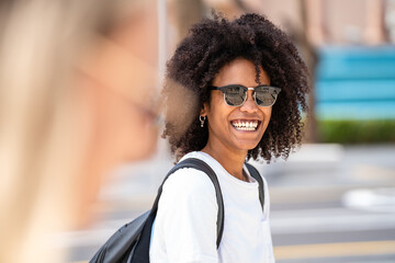 Portrait of natural smiling young woman with afro hairstyle wearing fashionable sunglasses, posing...