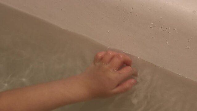 closeup of little hand of a girl swimming in bath. Arm in water moving