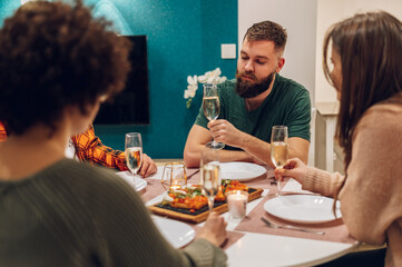 Group of friends enjoying dinner while sitting at the kitchen table together