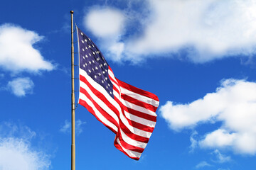 huge large waving american flag flagpole blue sky america holiday raised flying windy pride symbol red white blue clear wind tall stars stripes - Powered by Adobe