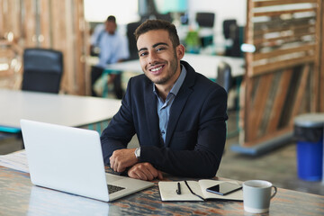 Fototapeta premium Its going to be another productive day. Portrait of a young businessman working on a laptop in an office.