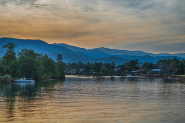 a village on the river and a layer of mountains at sunrise