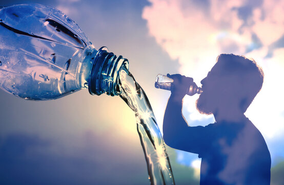 Drinking water and staying hydrated concept. Man drinking  bottle of water on blue sky background 