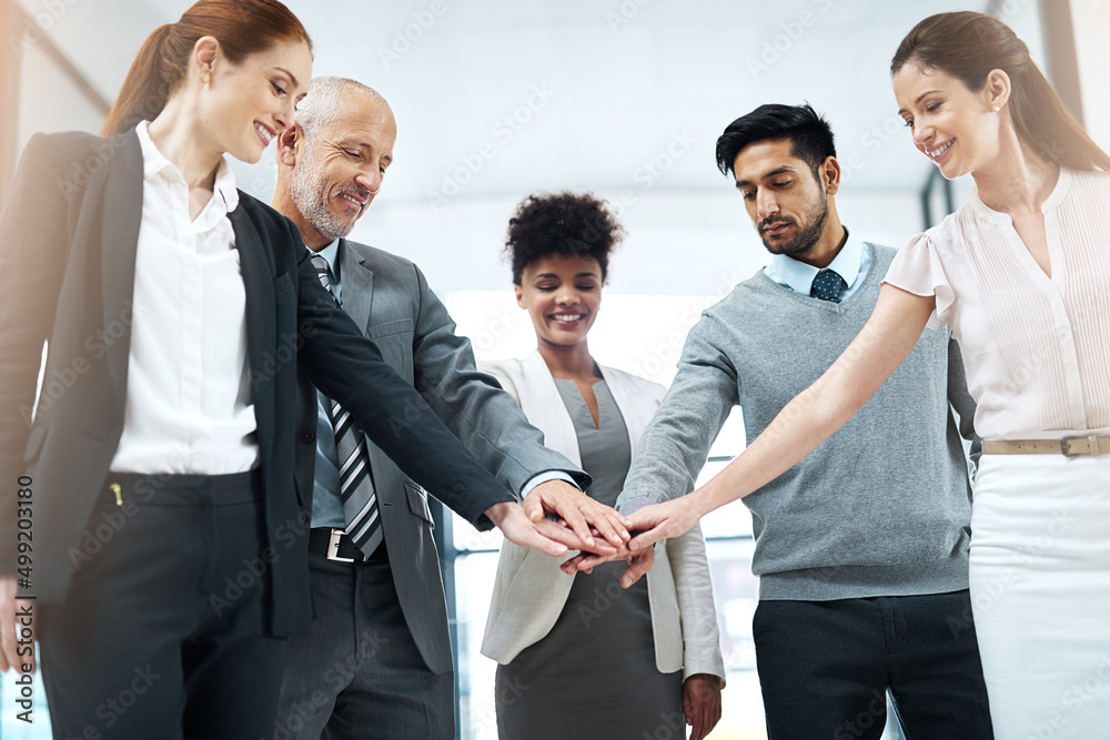 Poster success is even better when its shared. shot of a diverse team of colleagues joining their hands tog