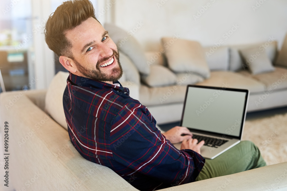 Poster winding down online. shot of a relaxed young man using a laptop on the sofa at home.