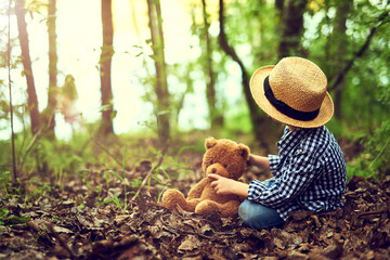 Shh Teddy, I heard something. Shot of a little boy sitting in the forest with his teddy bear.