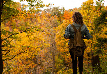 Woman in the forest with a backpack in autumn 