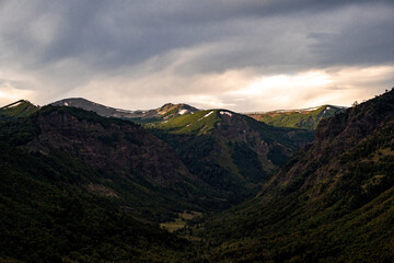 Green and snowy mountain valley with sunset illuminating the peaks, Chile