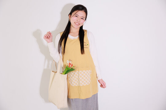 買い物袋を持つエプロンを着た日本人女性