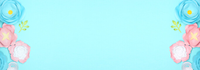 Beautiful handmade paper flowers on light blue background with space for text