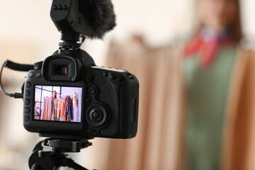 Young female clothes stylist recording video in studio, view on screen of modern video camera
