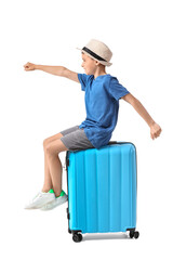 Adorable little boy sitting on suitcase against white background