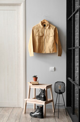 Stepladder stool with shoes and jacket hanging on light wall in hallway