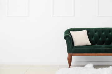 New green sofa with pillow near white wall