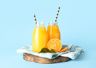 Bottles of fresh tangerine juice on blue background