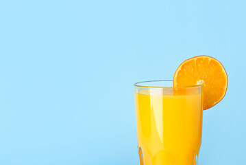 Glass of fresh tangerine juice on blue background