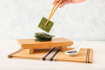 Woman eating tasty seaweed sheets at table © Pixel-Shot