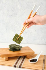 Woman eating tasty seaweed sheets at table © Pixel-Shot