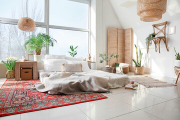 Interior of cozy bedroom with houseplants and carpets