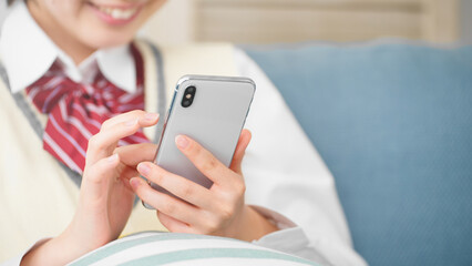 ソファーでスマートフォンを操作する女子高生