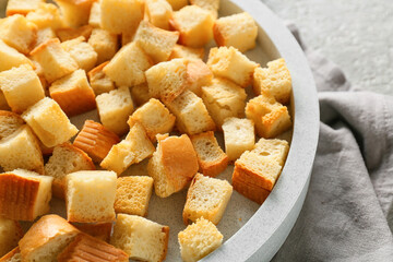 Bowl with tasty croutons and napkin on light background, closeup