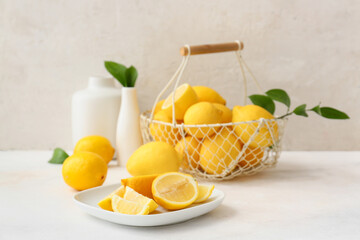 Plate and basket with fresh lemons on light table