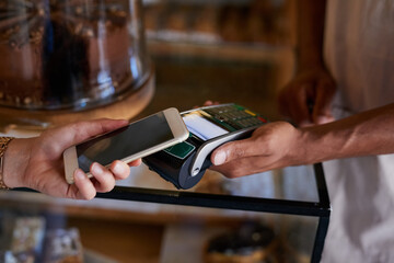 Gone are the days of carrying cash on you. Closeup shot of a customer paying using NFC technology in cafe.