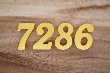Golden Arabic numerals on a real brown and white wooden floor number 7286