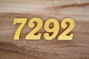 Golden Arabic numerals on a real brown and white wooden floor number 7292