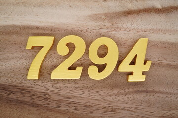 Golden Arabic numerals on a real brown and white wooden floor number 7294