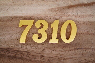 Golden Arabic numerals on a real brown and white wooden floor number 7310