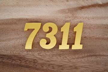 Golden Arabic numerals on a real brown and white wooden floor number 7311