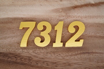 Golden Arabic numerals on a real brown and white wooden floor number 7312