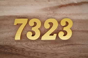 Golden Arabic numerals on a real brown and white wooden floor number 7323