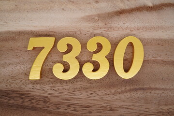 Golden Arabic numerals on a real brown and white wooden floor number 7330