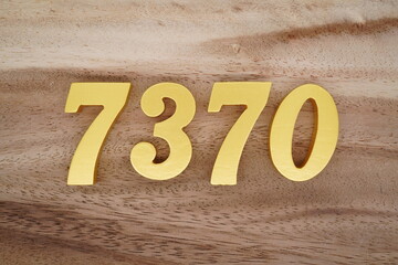 Golden Arabic numerals on a real brown and white wooden floor number 7370