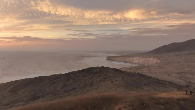 Aerial view of the Puerto Eten lighthouse and two motorcyclists. at sunset, Lambayeque, Peru